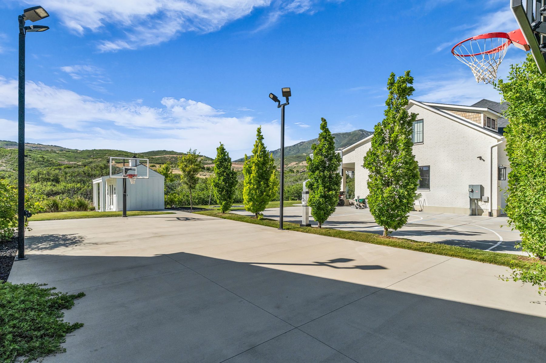 Full basketball court at 12517 N Minots Ledge Dr Highland Utah with lights and mountain backdrop